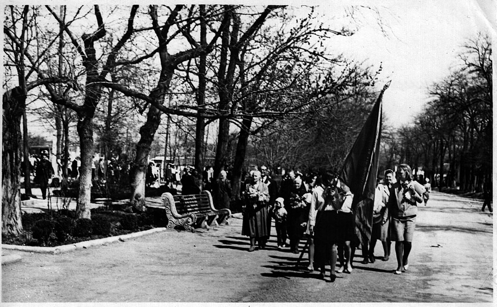 Колонна пионеров и ветеранов шествует вдоль мемориала погибшим партизанам и мирным жителям города во время праздника, посвящённого дню освобождения города. 1970-е годы.